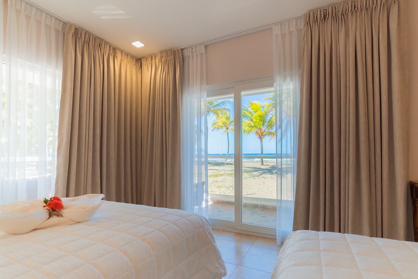 Habitación con cama de flores de toalla y vista a la playa